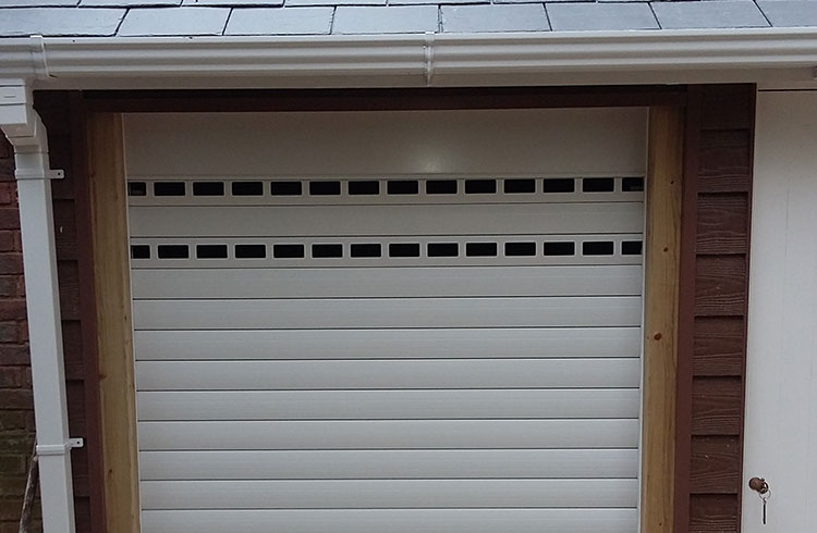 A Gliderol manual insulated roller shutter garage door fitted to a bin store with punched and unglazed slats for ventilation