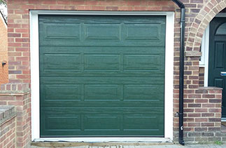 A Carteck Georgian sectional garage door in Fir green. Fitted within the brick work but behind the lintel, complete with a white steel frame and white UPVC as required.