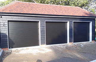 Three Sws Seceuroglide Excel roller shutter garage doors in a Black Wood grain finish. On White slats. Fitted in Ascot, Berkshire.