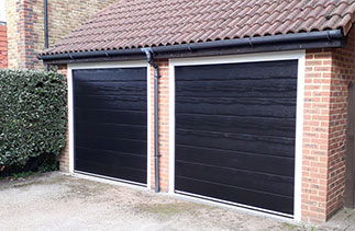 Two Carteck Centre Ribbed Black wood grain sectional garage doors with White steel frames fitted in Warfield, Berkshire. Simply a great end to end customer service experience, just like it should be. Mr A Burns.